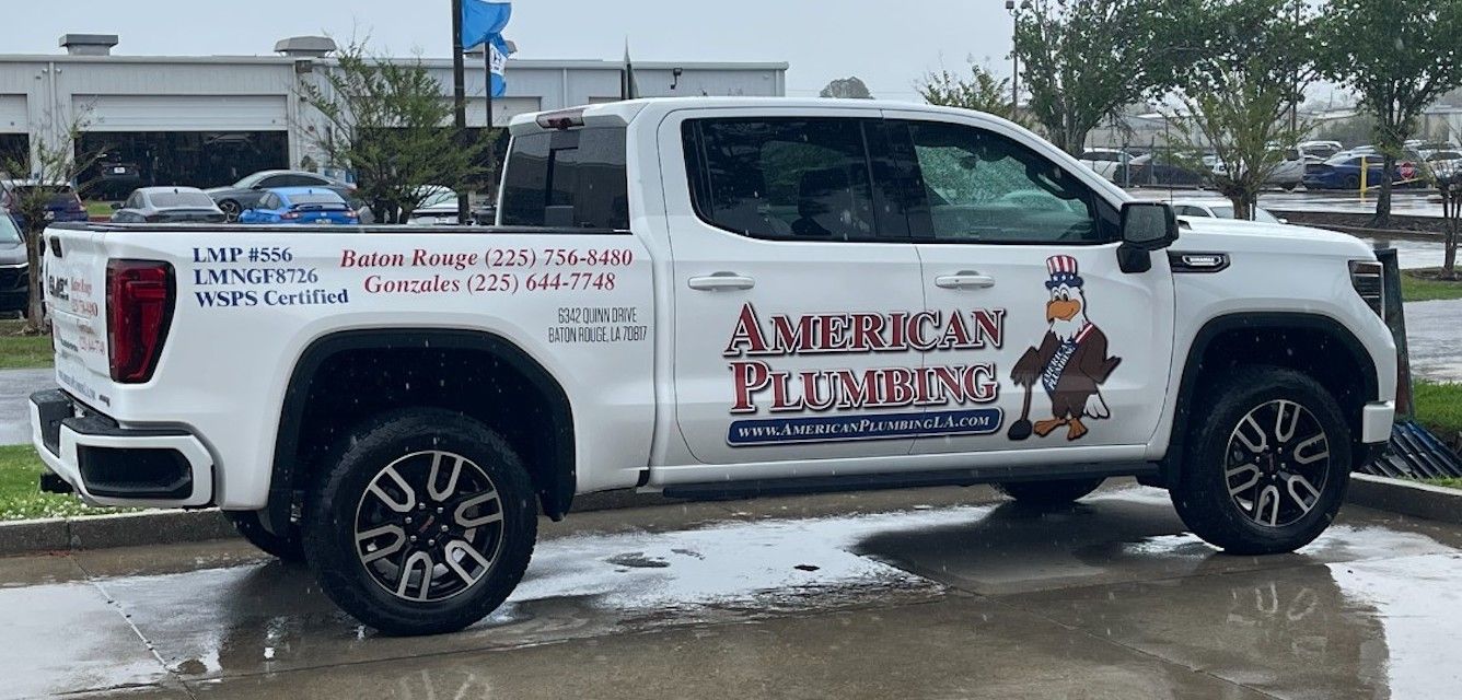 White pickup truck with plumber business graphics parked on a wet street in winter