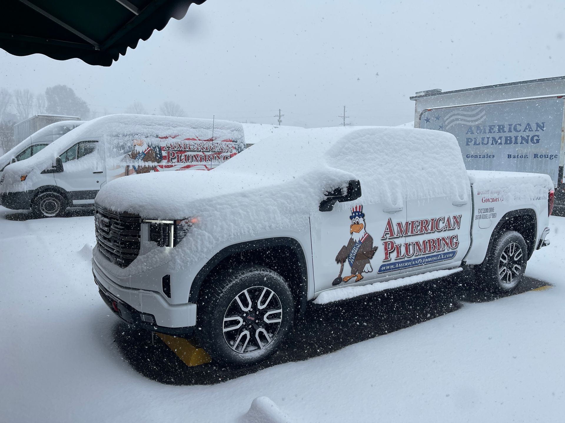 Snow-covered white pickup truck with holiday graphics parked in a snowy lot