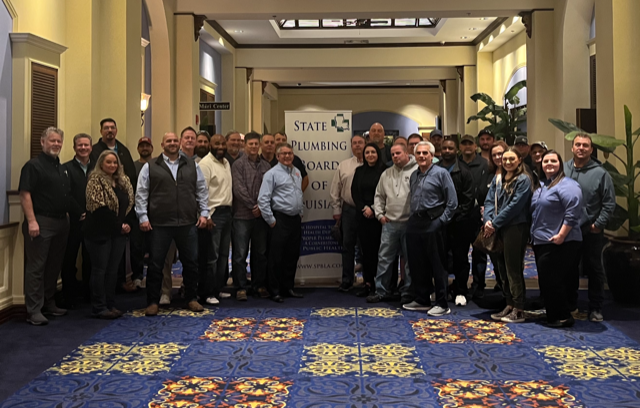 Group of people posing in a hallway in front of a banner that reads
