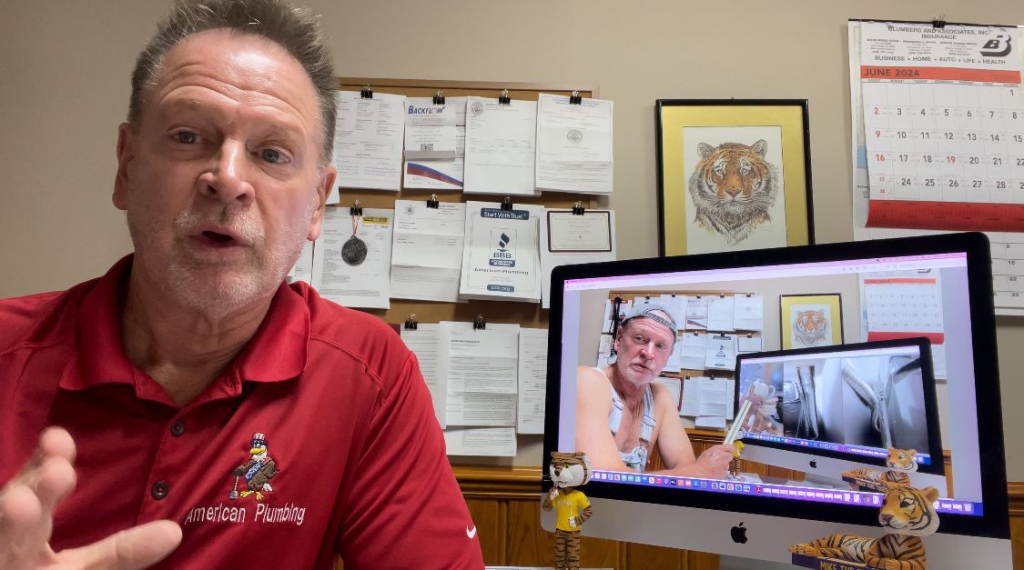 Man in red polo speaking beside a laptop displaying a video call in an office