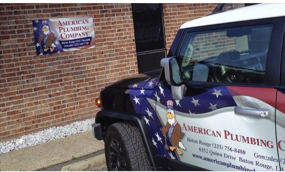 American Plumbing van parked by a brick building with matching company sign