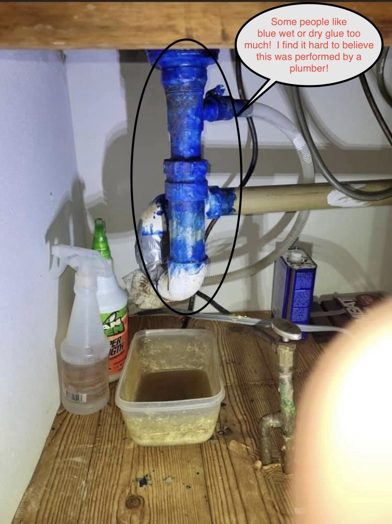 Blue PVC plumbing under a cabinet with a speech bubble saying,