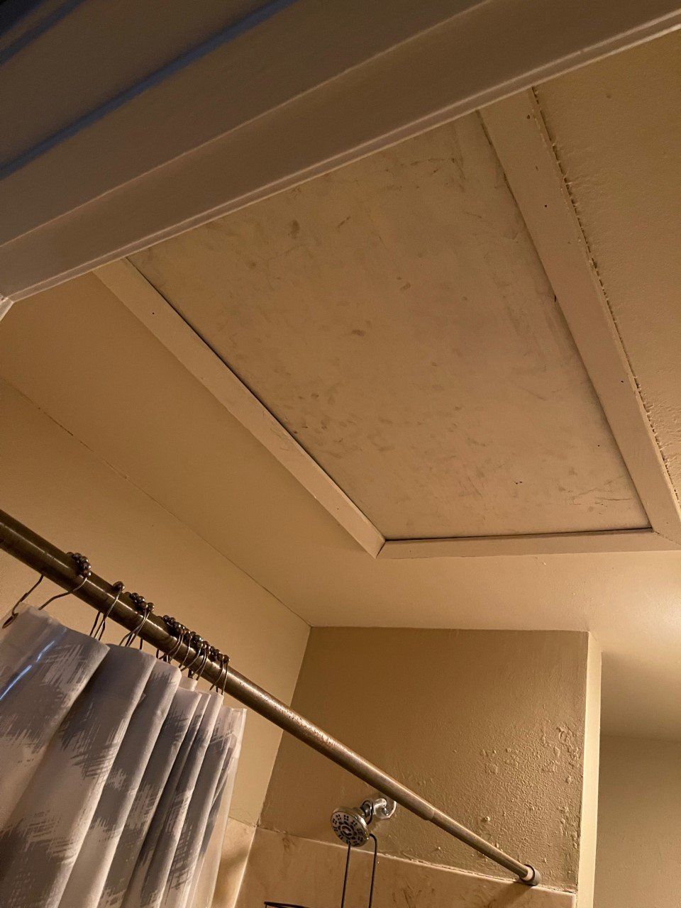Ceiling corner above a shower curtain rod and tiled shower area