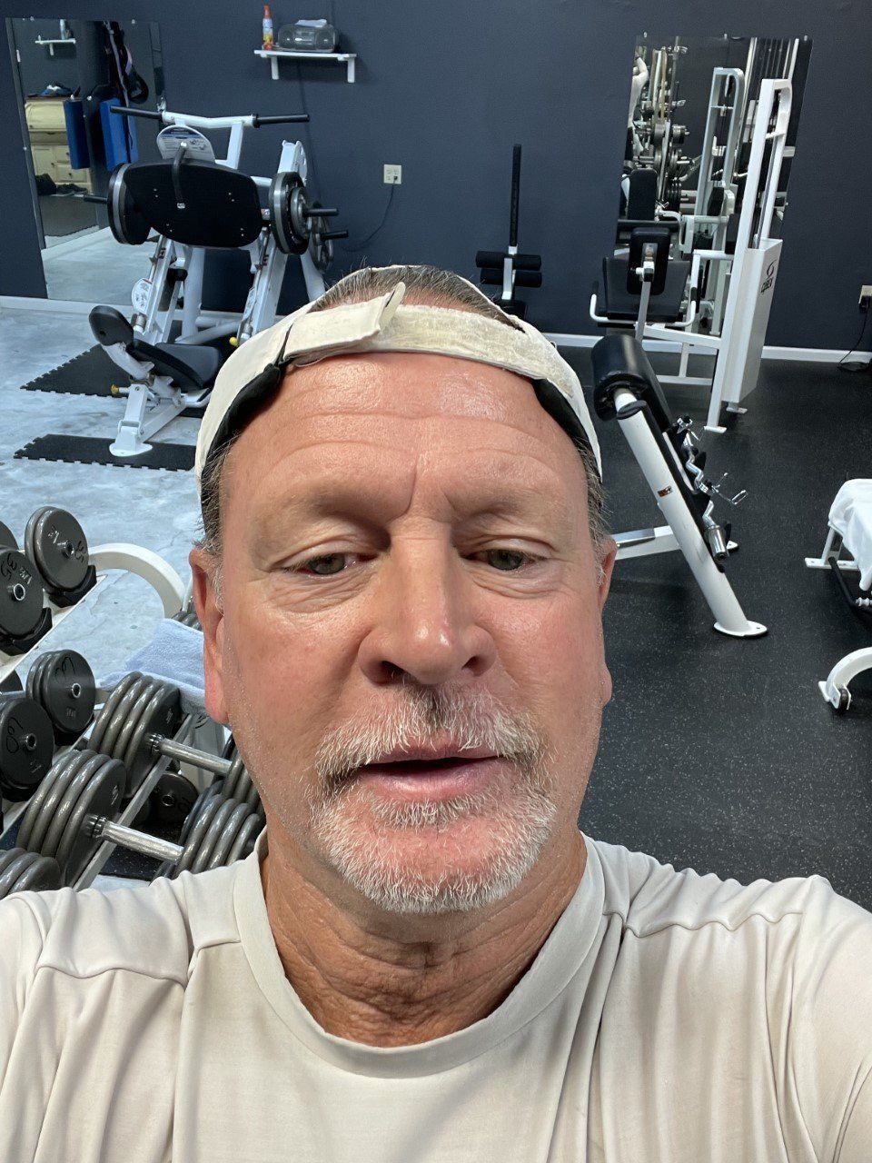 Selfie in a gym with exercise equipment and dumbbells in the background