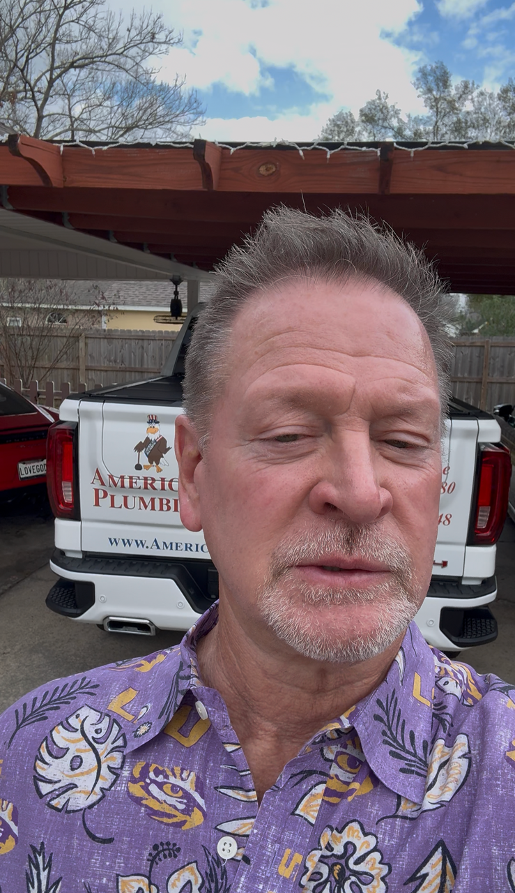 Man in a purple shirt taking a selfie in front of a pickup truck under a carport