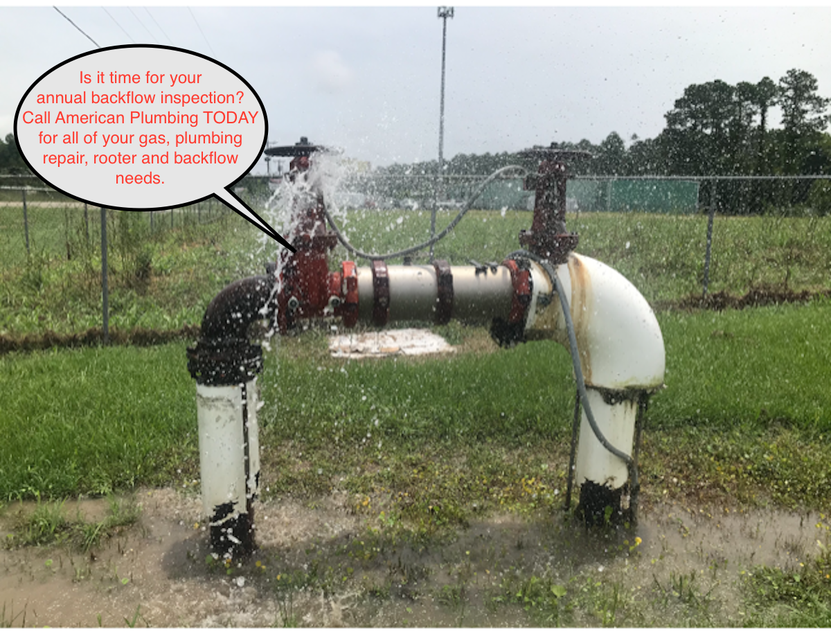 Irrigation valve assembly spraying water in a grassy field, with a small warning sign.