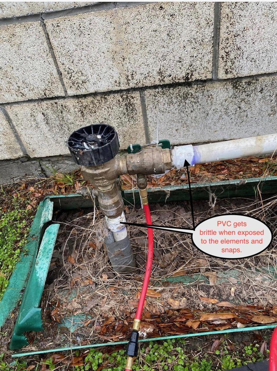 Sprinkler system with exposed PVC pipe, green box, red hose.