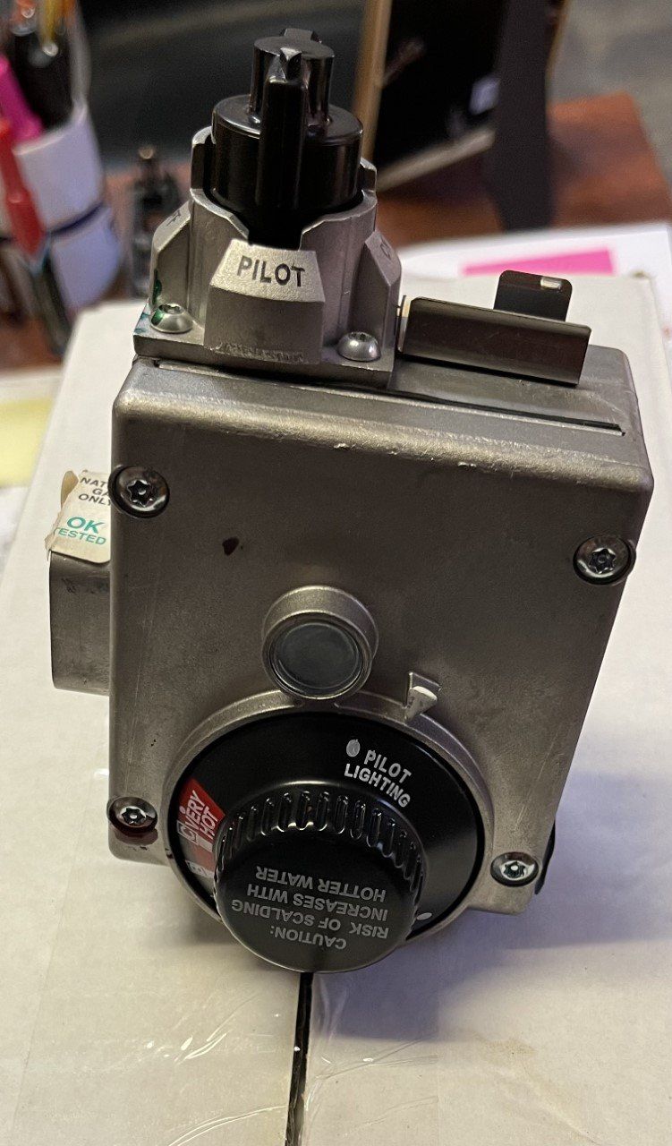 Close-up of a gray metal control box with a pilot switch and black rotary knob on a table