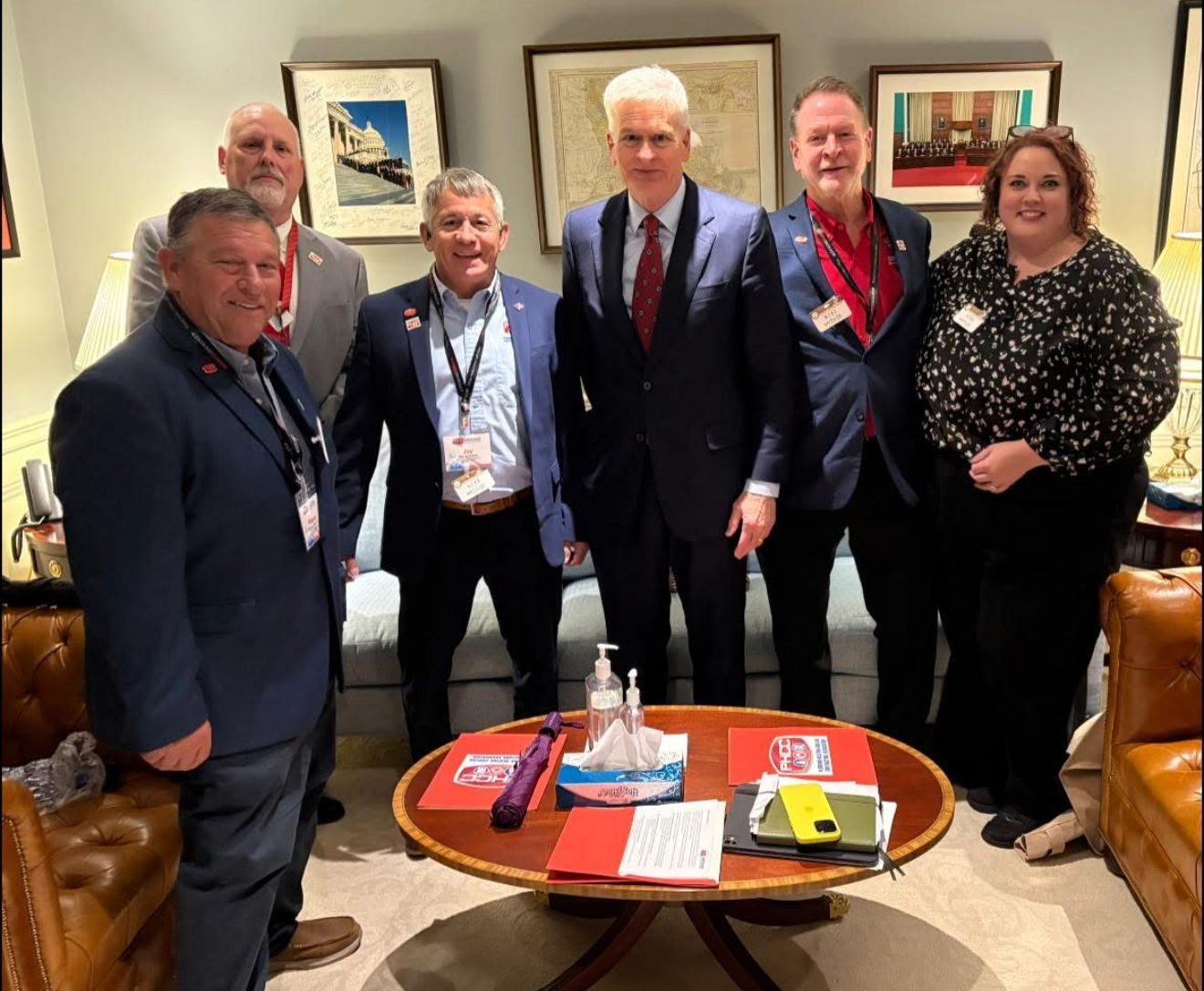 Five people posing in a living room around a coffee table with books and papers.