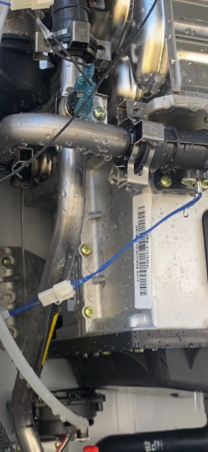 Close-up of a silver appliance interior with blue wires and a white connector.