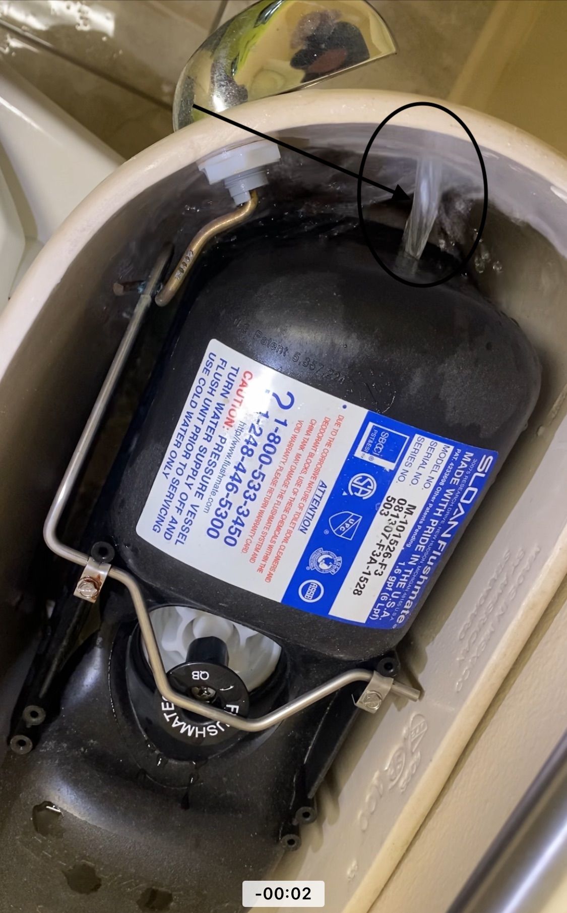 Close-up of a car battery in the engine bay with connected cables and warning labels.