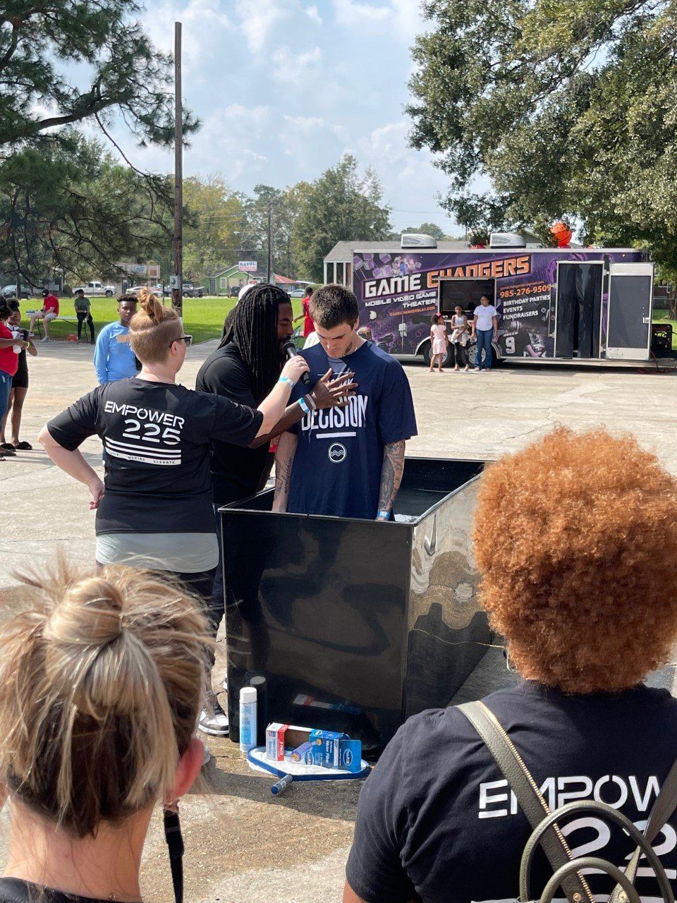 People gathered at an outdoor event near a food truck on a sunny day.