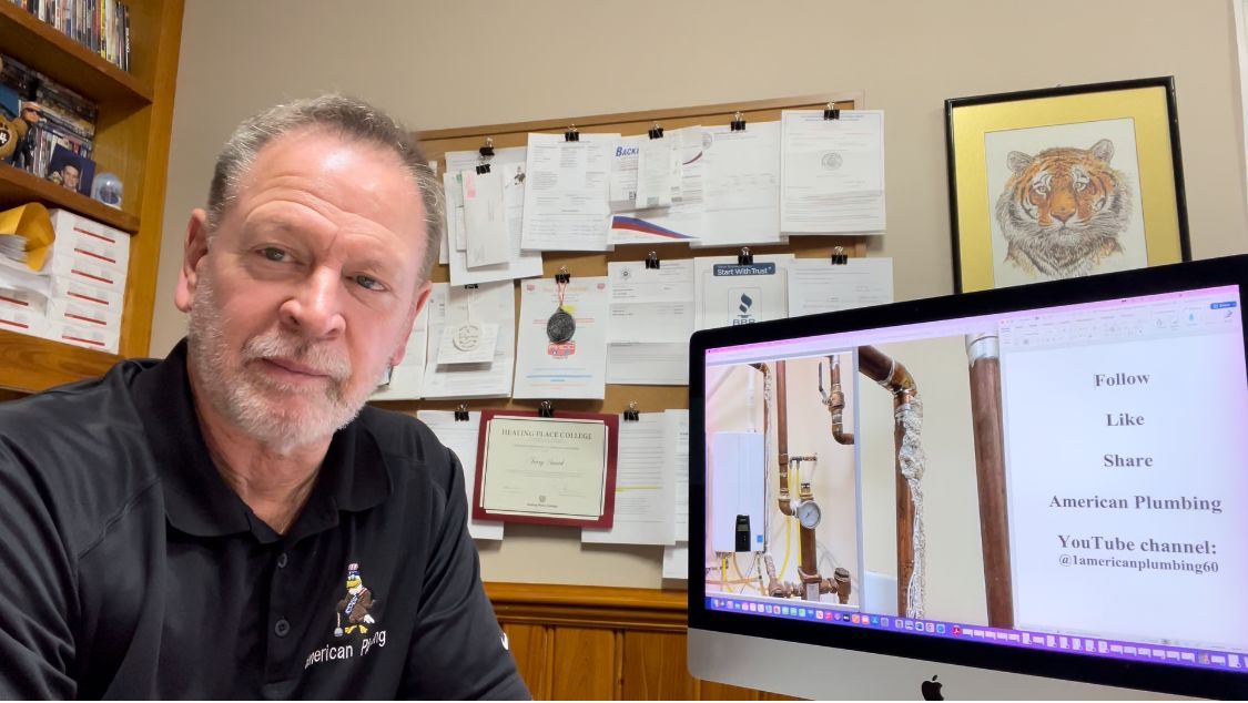 Man in black shirt in office, looking at screen with plumbing photos.