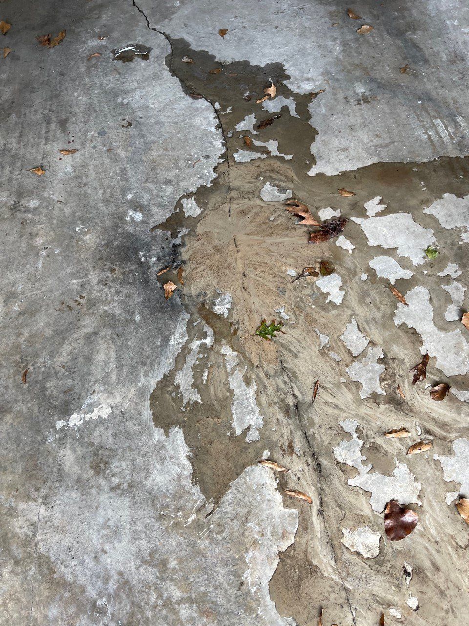 Damaged concrete floor with peeling paint and a rough patch of broken plaster.