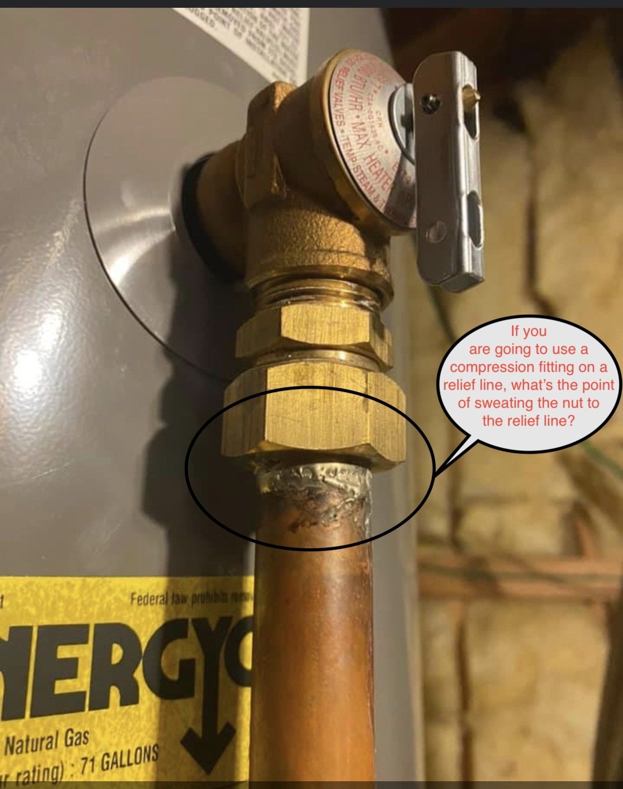 Close-up of a water heater's pressure relief valve. A copper pipe is connected to the valve.