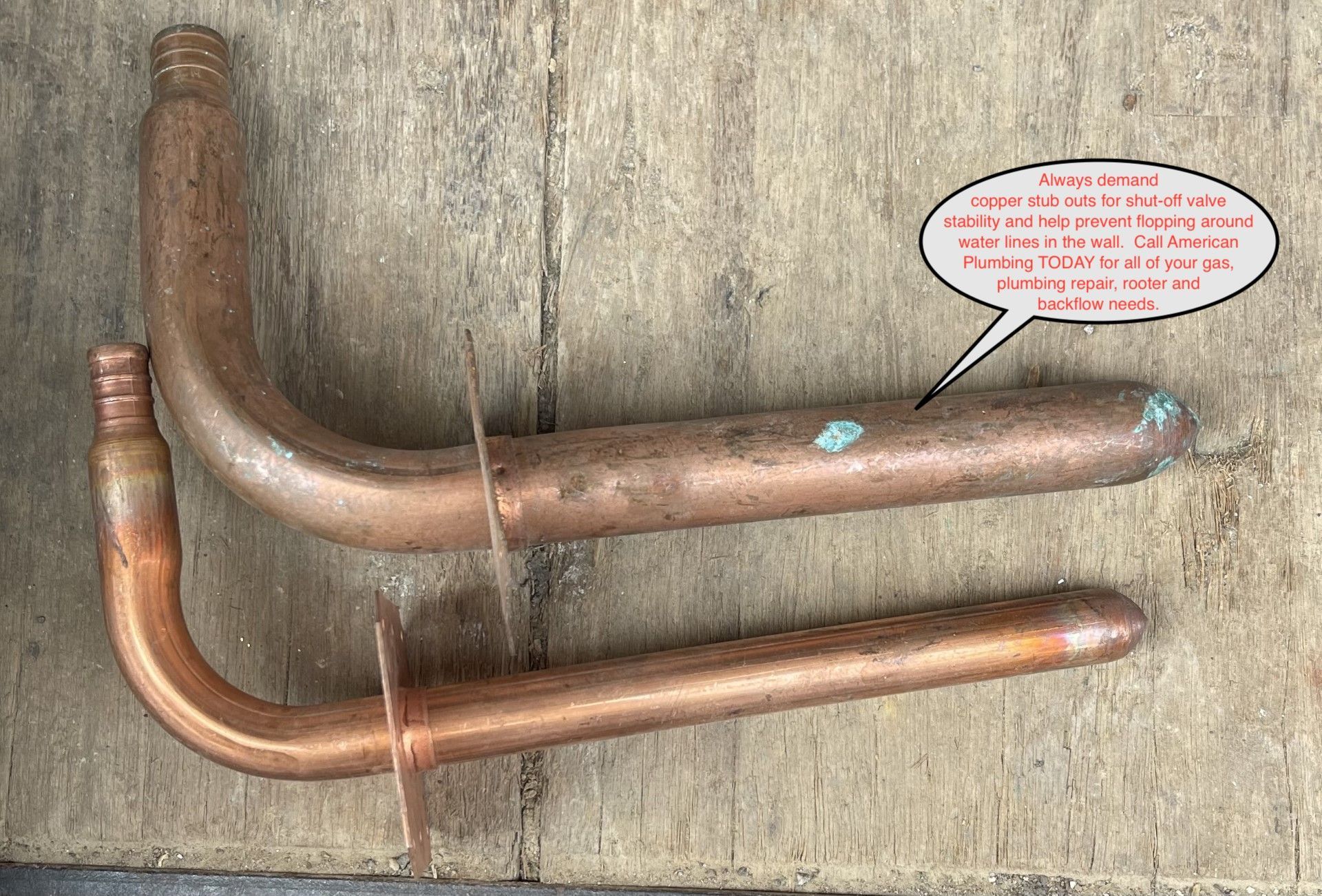 Two copper pipes on weathered wood, one bent with a curved top and one straight, with small blue markers.