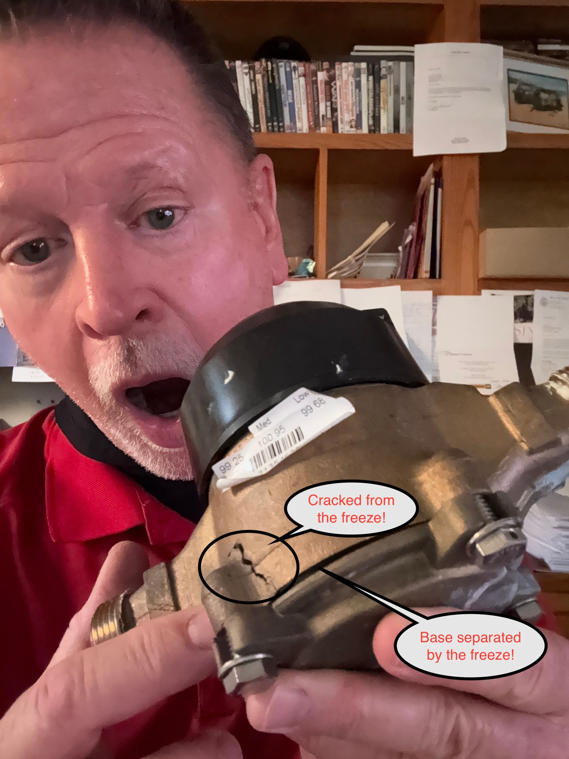 Man holding a brass pipe fitting with labeled callouts, mouth open in surprise, in a workshop.