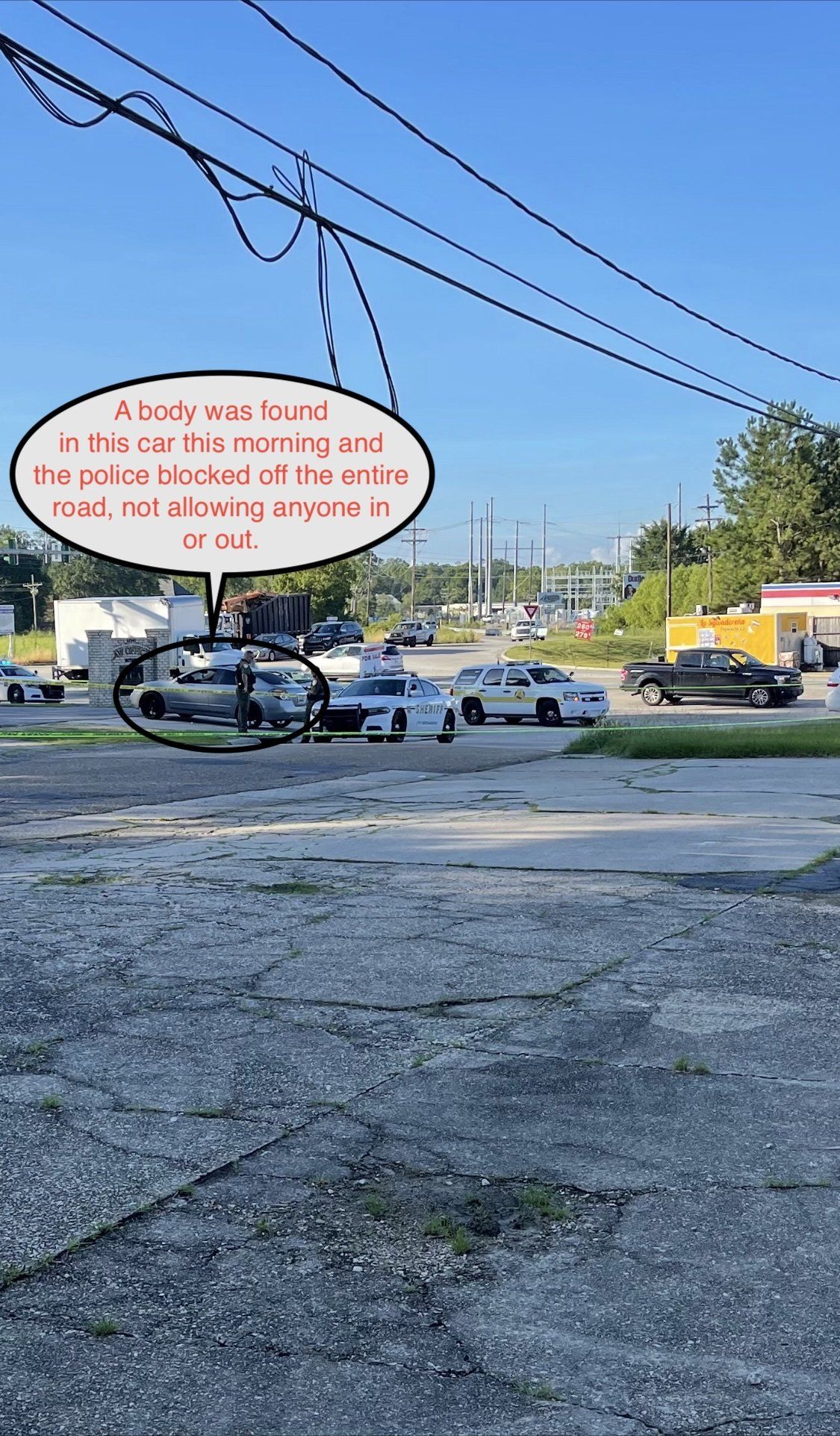 Protest sign near a road intersection with cars, utility wires, and a yellow building in the background
