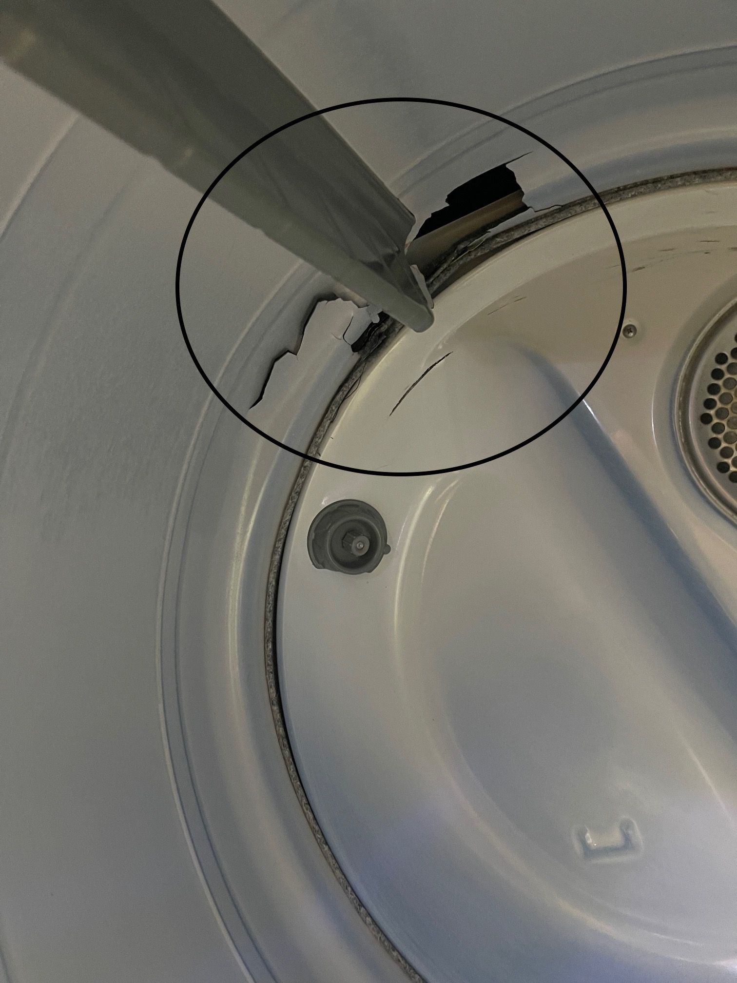 Inside a dryer drum, a metal bar and damaged interior.