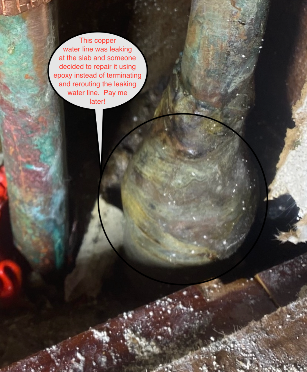Close-up of corroded green pipe and wrapped fitting inside a dark, rusty space, with a circled leak area.