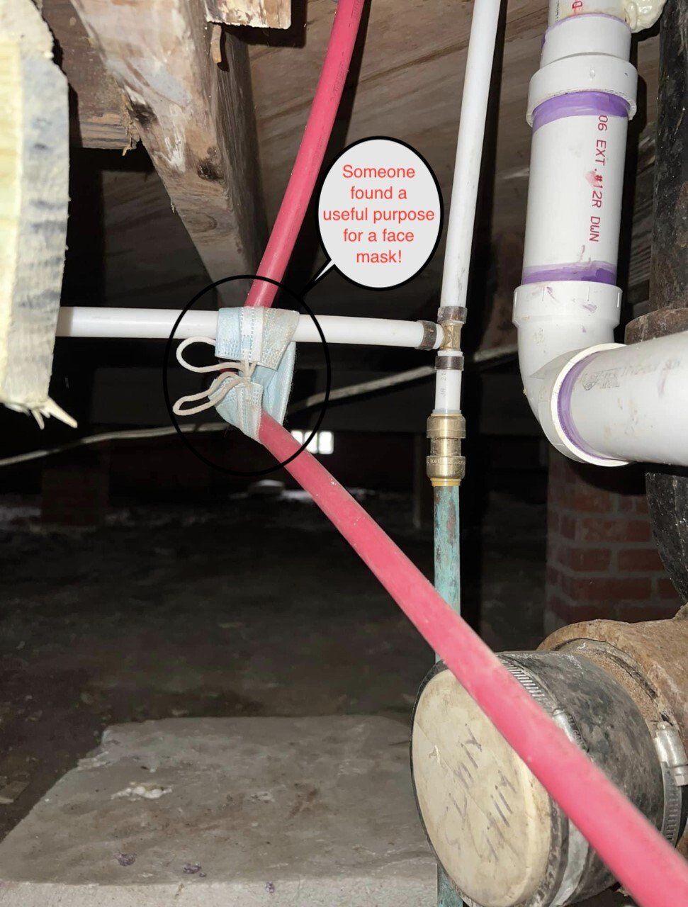 Basement with exposed plumbing pipes, a red strap, and a small warning tag near a concrete floor