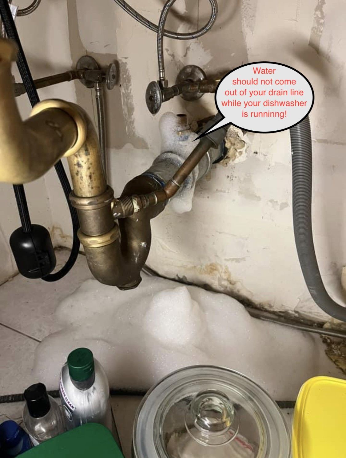 Under-sink plumbing with a speech bubble noting hot-water tubing should be insulated to save energy.
