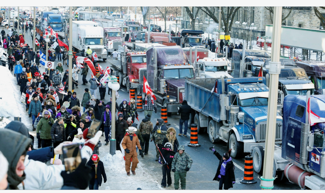 Ottawa street scene: Protesters and trucks fill the road, some holding Canadian flags in winter.