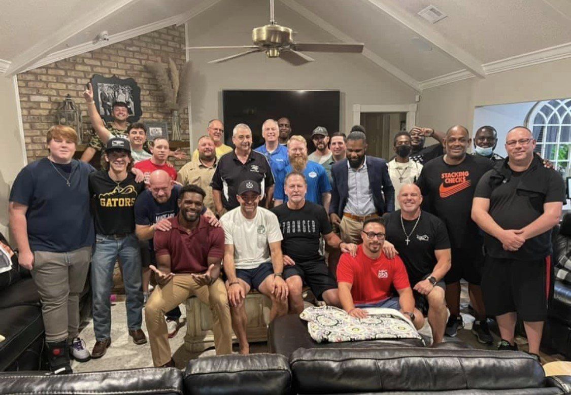 Large group posing together in a living room with a stone fireplace and black leather couches