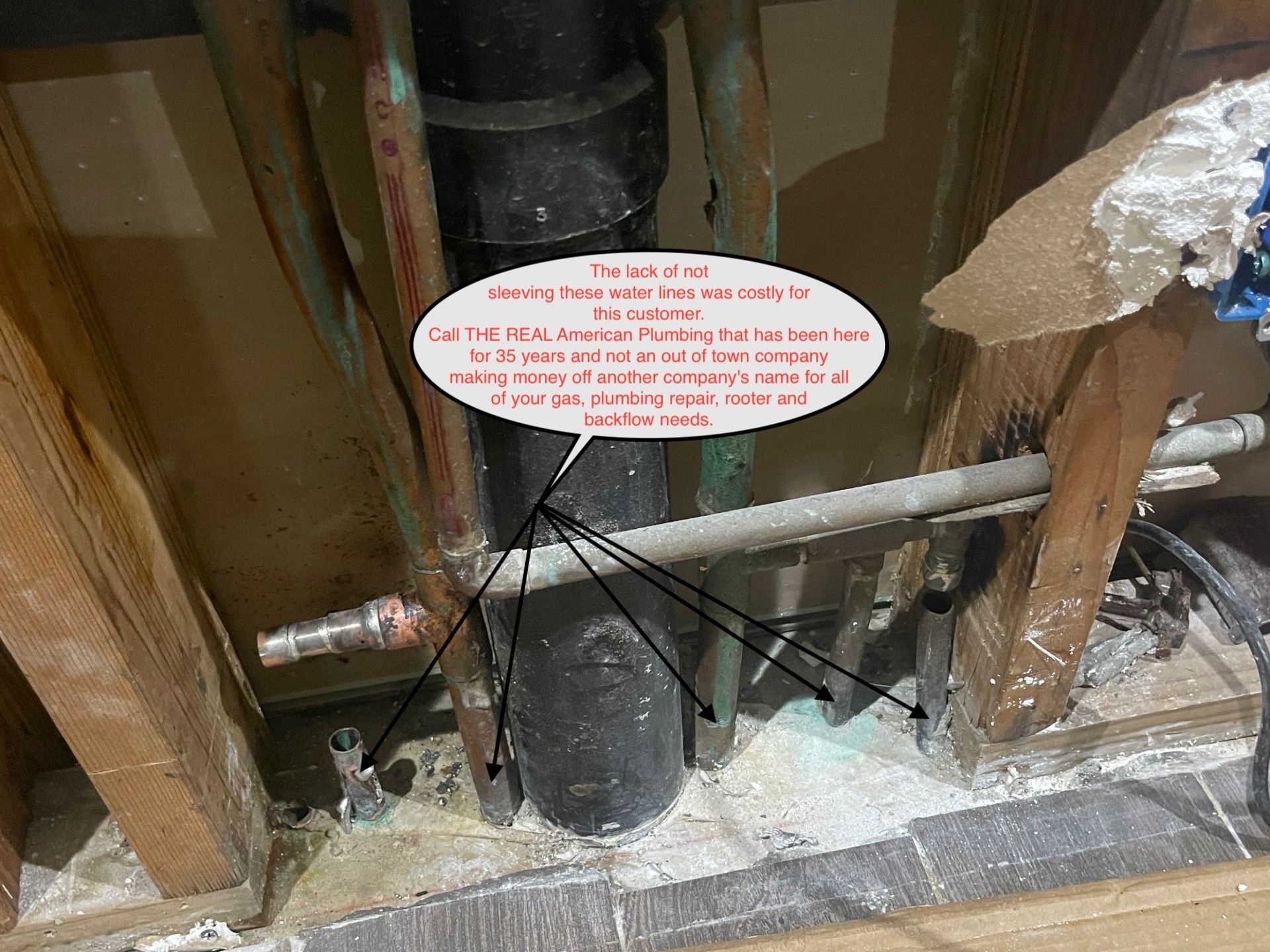 White warning sign on a black bucket in a wall cavity with exposed pipes and insulation debris.