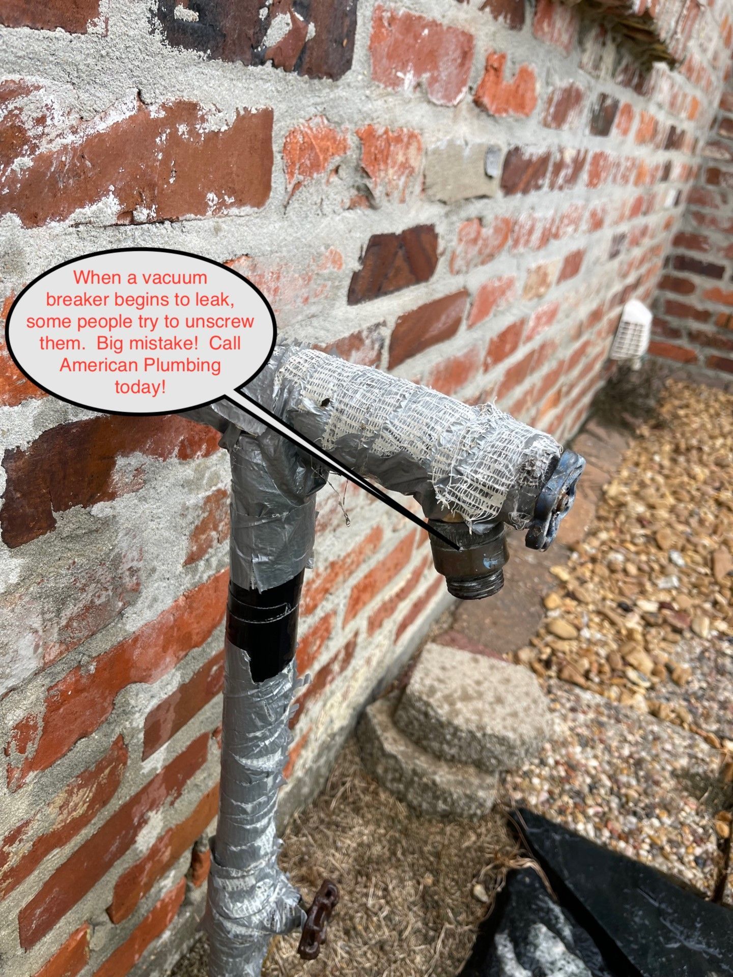 Exterior water spigot covered in corrosion and tape; near a brick wall and gravel.