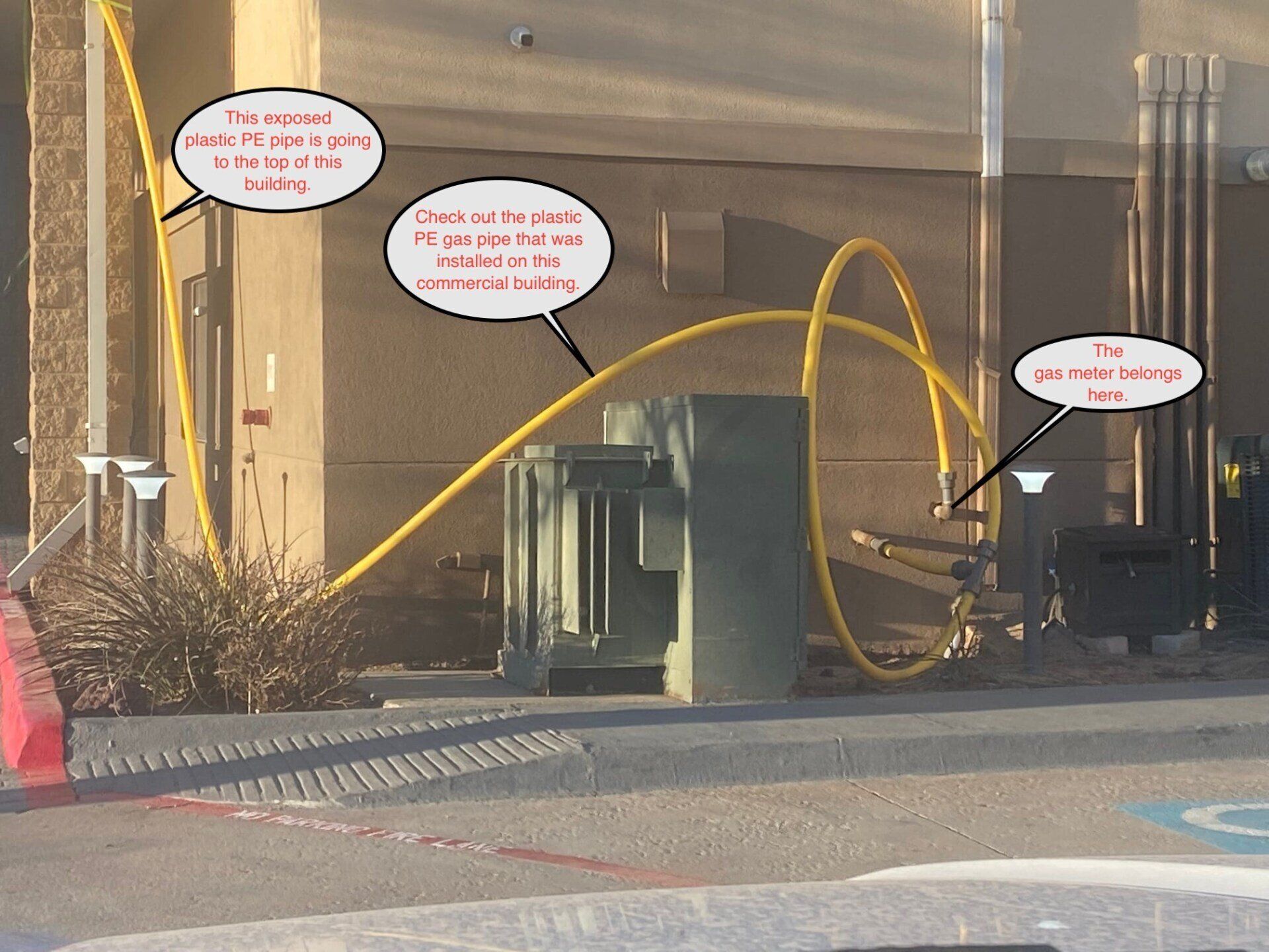 Yellow pipes running along a building wall and an electrical box, text annotations point to the lines and box.