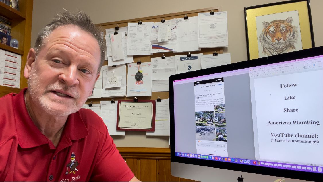 Man in red shirt beside monitor showing a document in an office with papers pinned on the wall