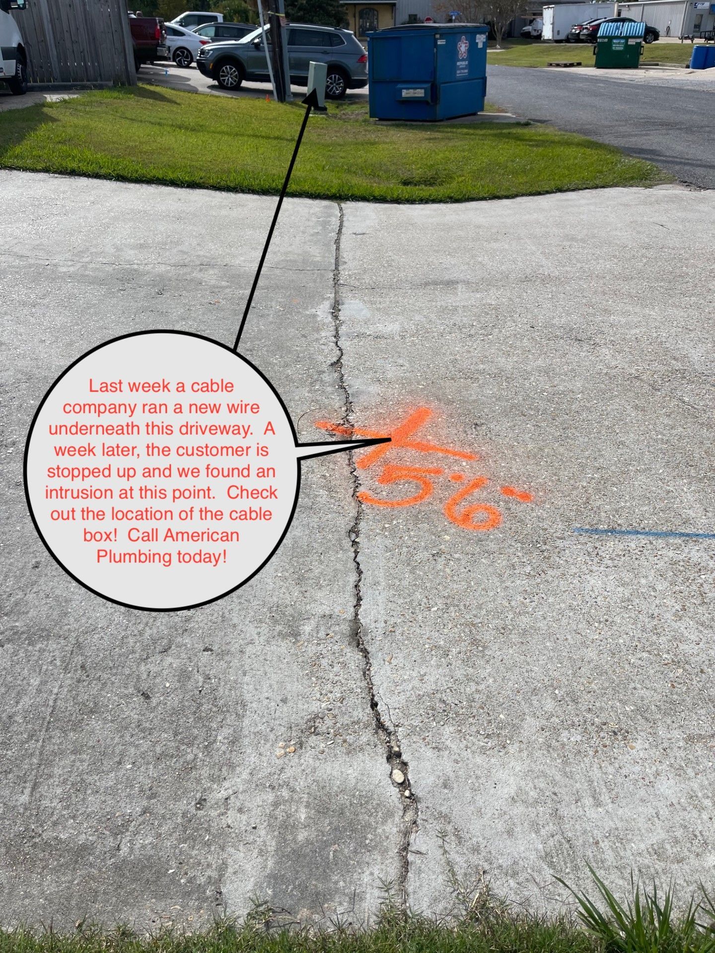 Driveway crack with orange paint and text: cable line damage.