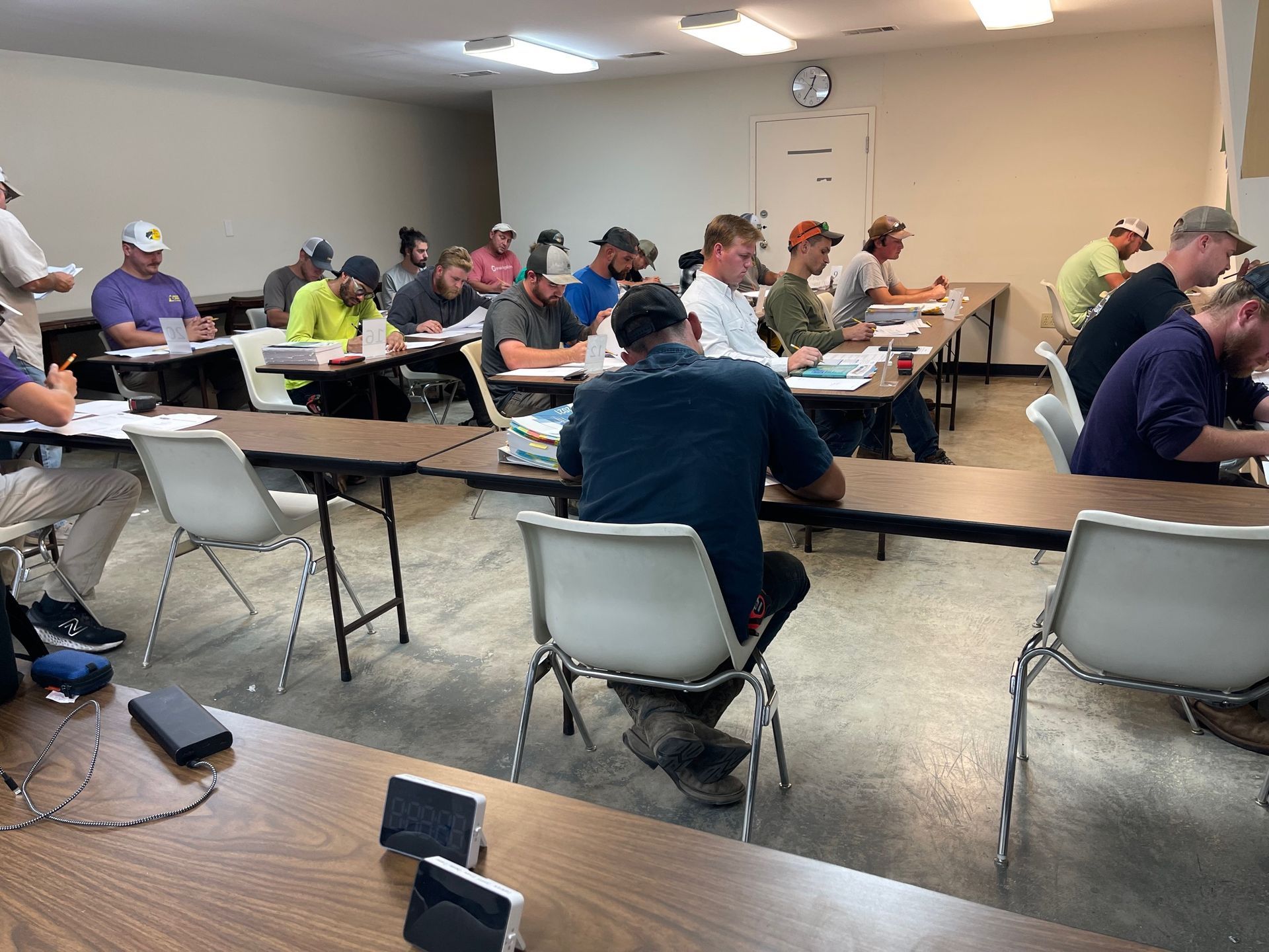People seated at tables in a meeting room, taking notes during a class or workshop.