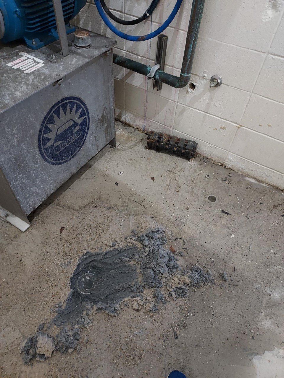 Dirty concrete floor with a gray spill or debris near a wall and industrial equipment