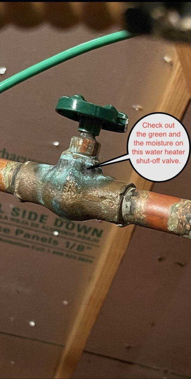 Green faucet handle on a rusted copper pipe with a small pink label attached.