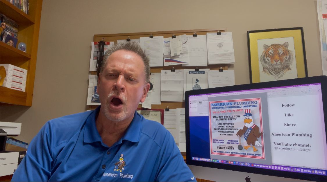 Man in blue shirt speaking, with a computer screen showing a flyer and a bulletin board in the background.