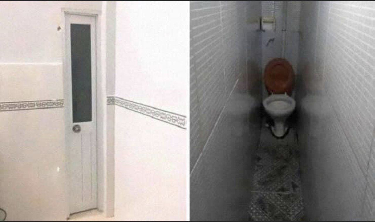 Narrow tiled bathroom with a white door and a toilet at the end of a very tight stall.