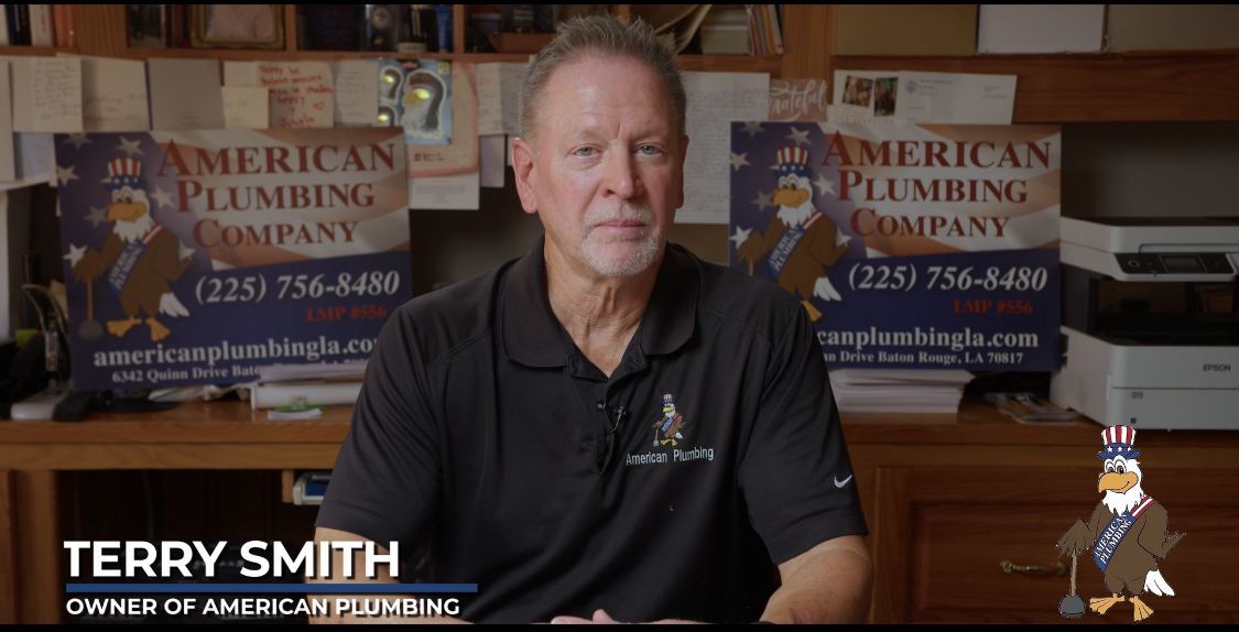 Terry Smith, owner of American Plumbing Co., in front of business sign.