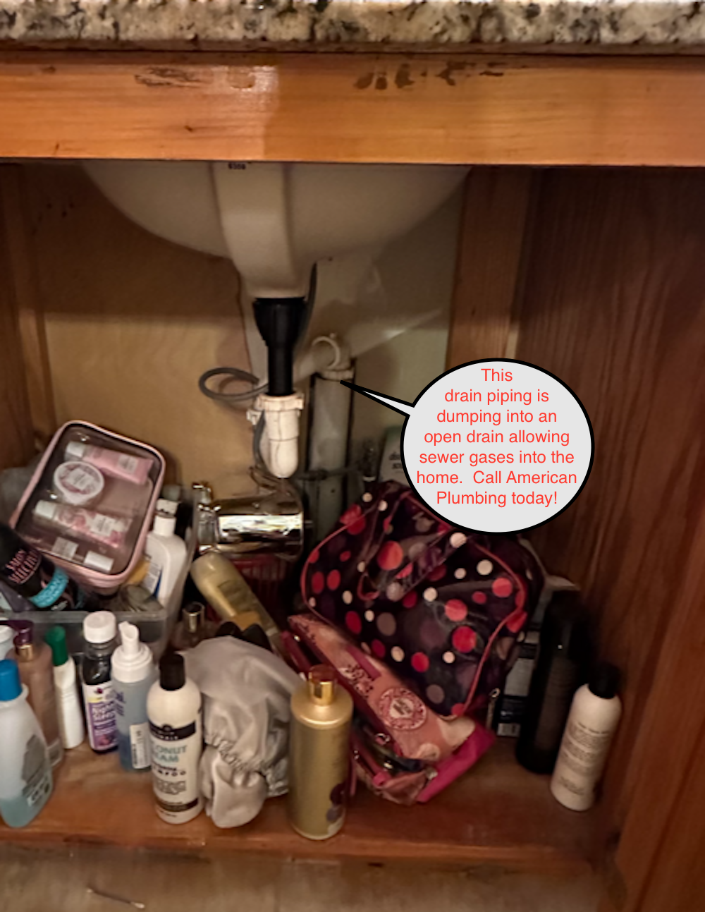 Bathroom vanity under the sink; plumbing, toiletries, and makeup clutter the storage space.