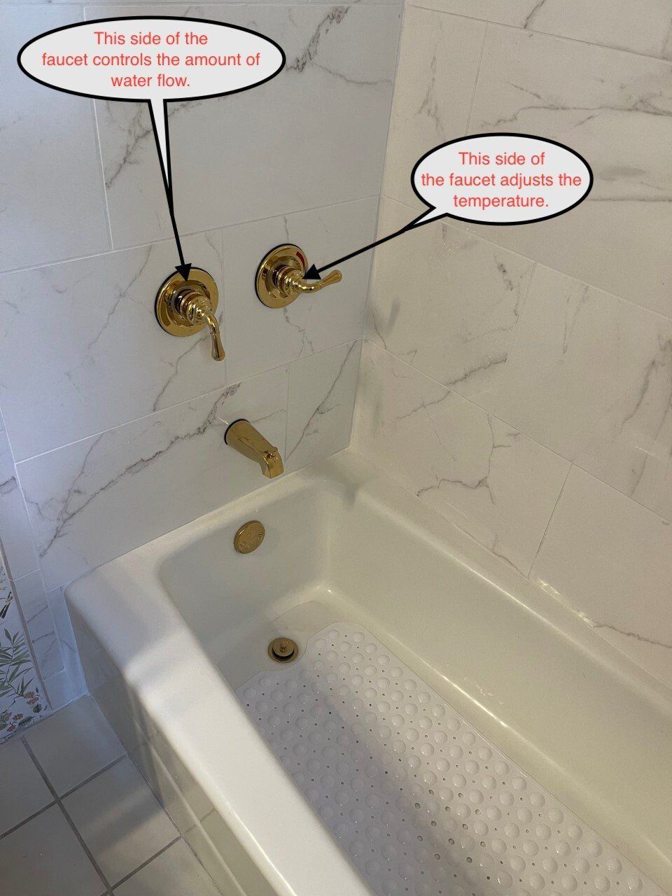 Gold bathtub fixtures on white marble wall. One faucet controls water flow, the other adjusts temperature.