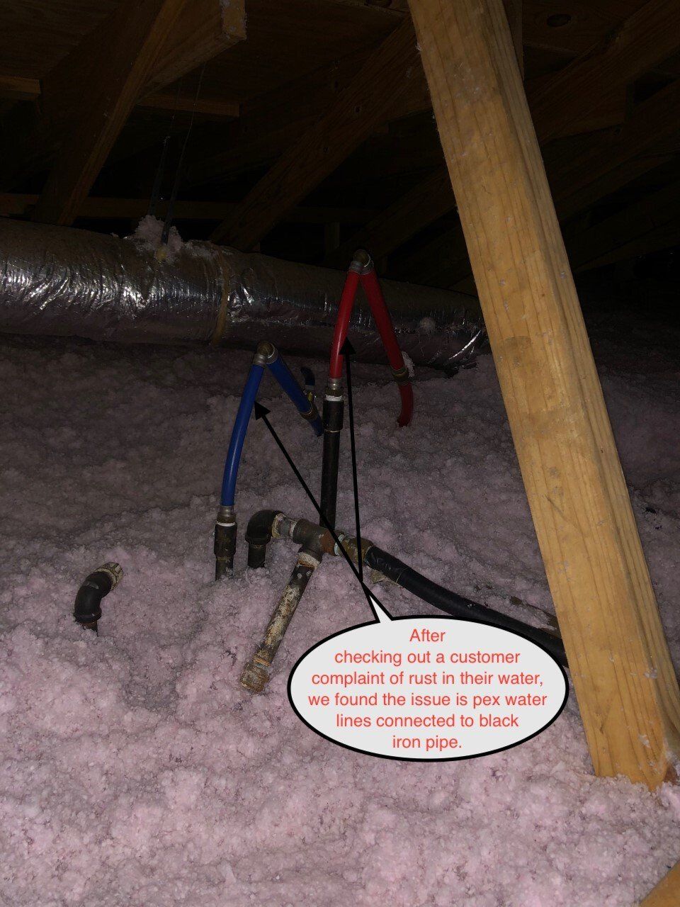 Tripod under a crawlspace next to a duct, with a small warning sign on the pink insulation floor.