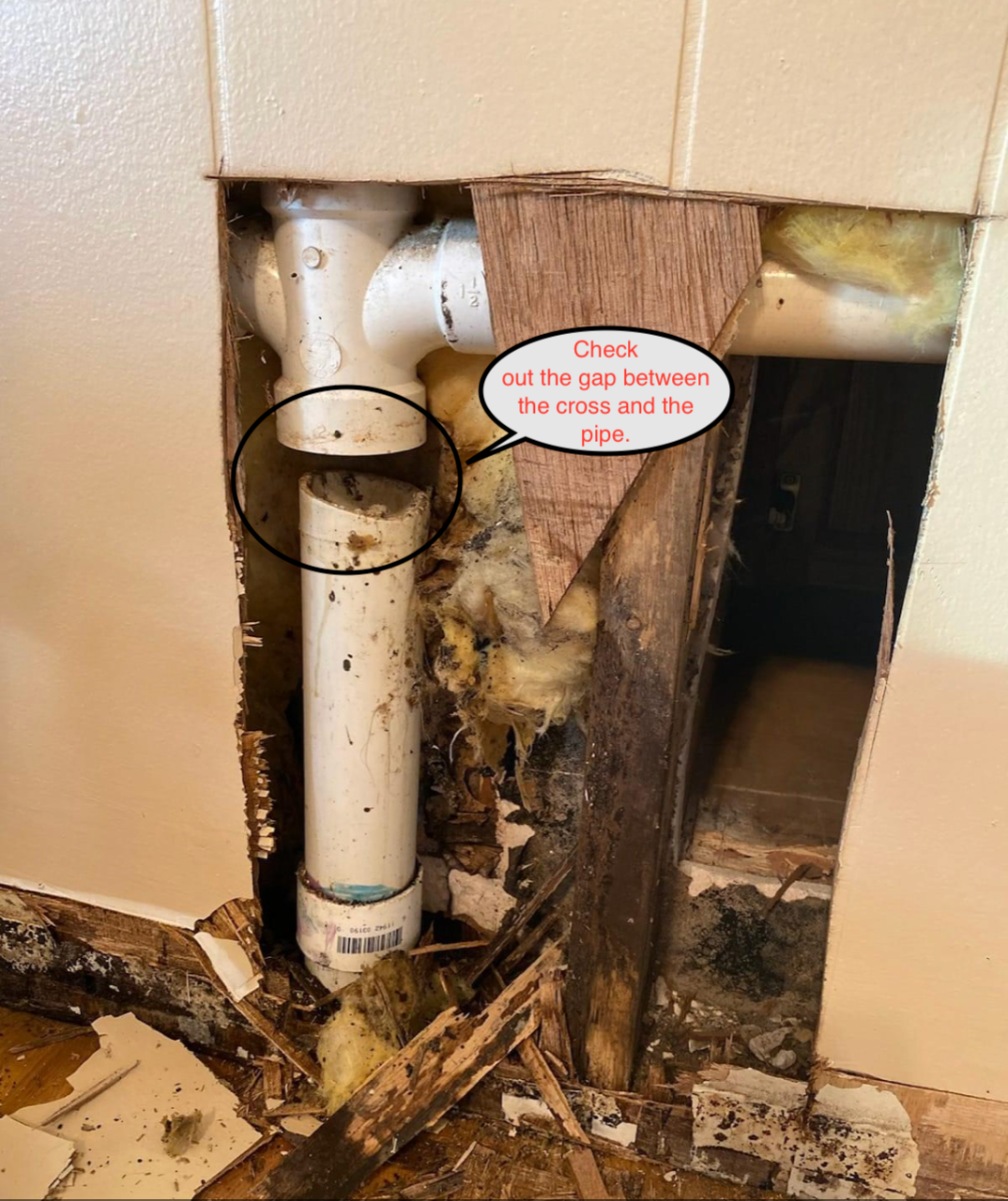 Damaged wall exposing pipes and rotted wood, with a warning label pointing to mold or water damage.