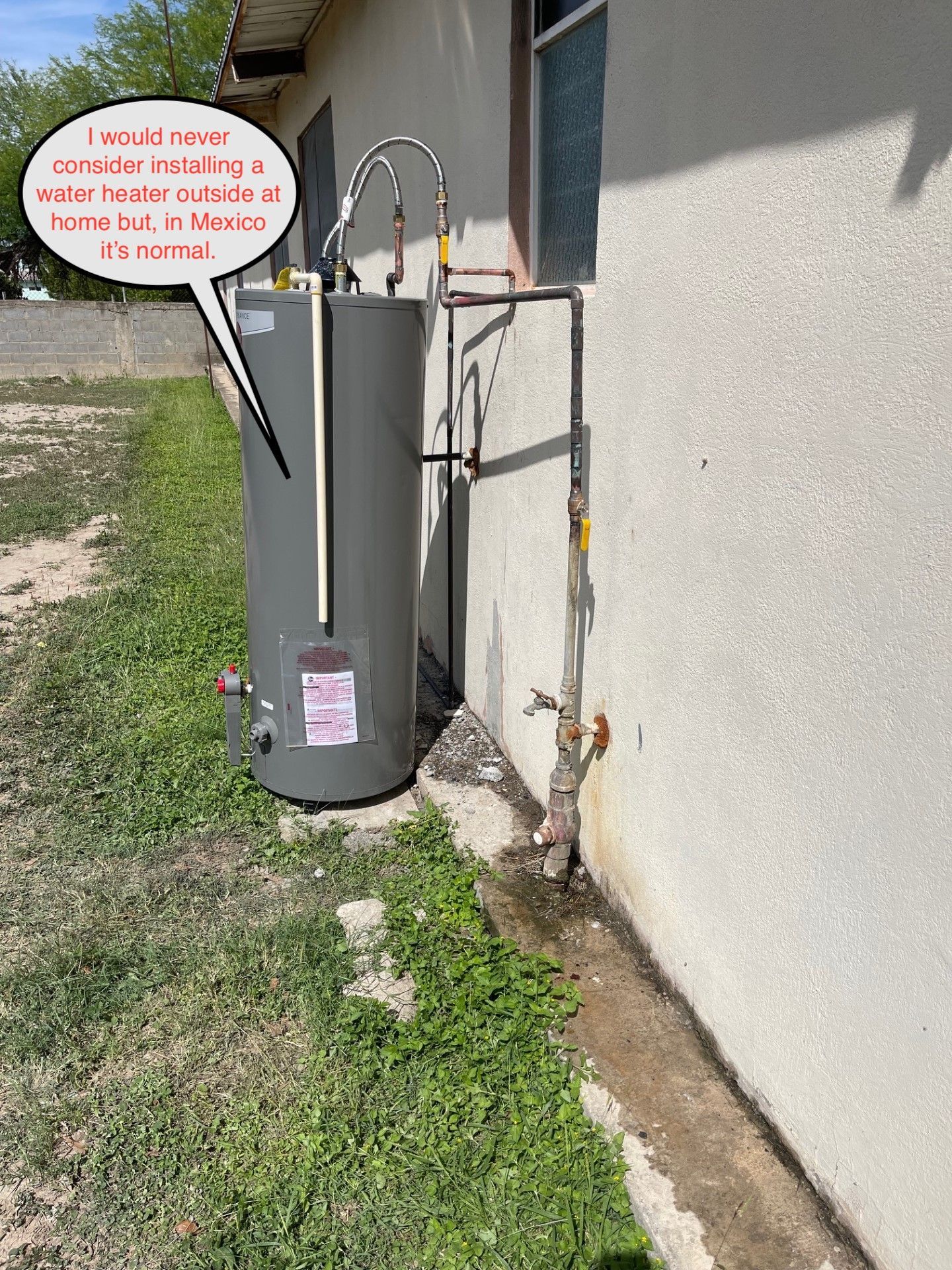 Water heater installed outside a house; Texas. White wall, grass, and text bubble.