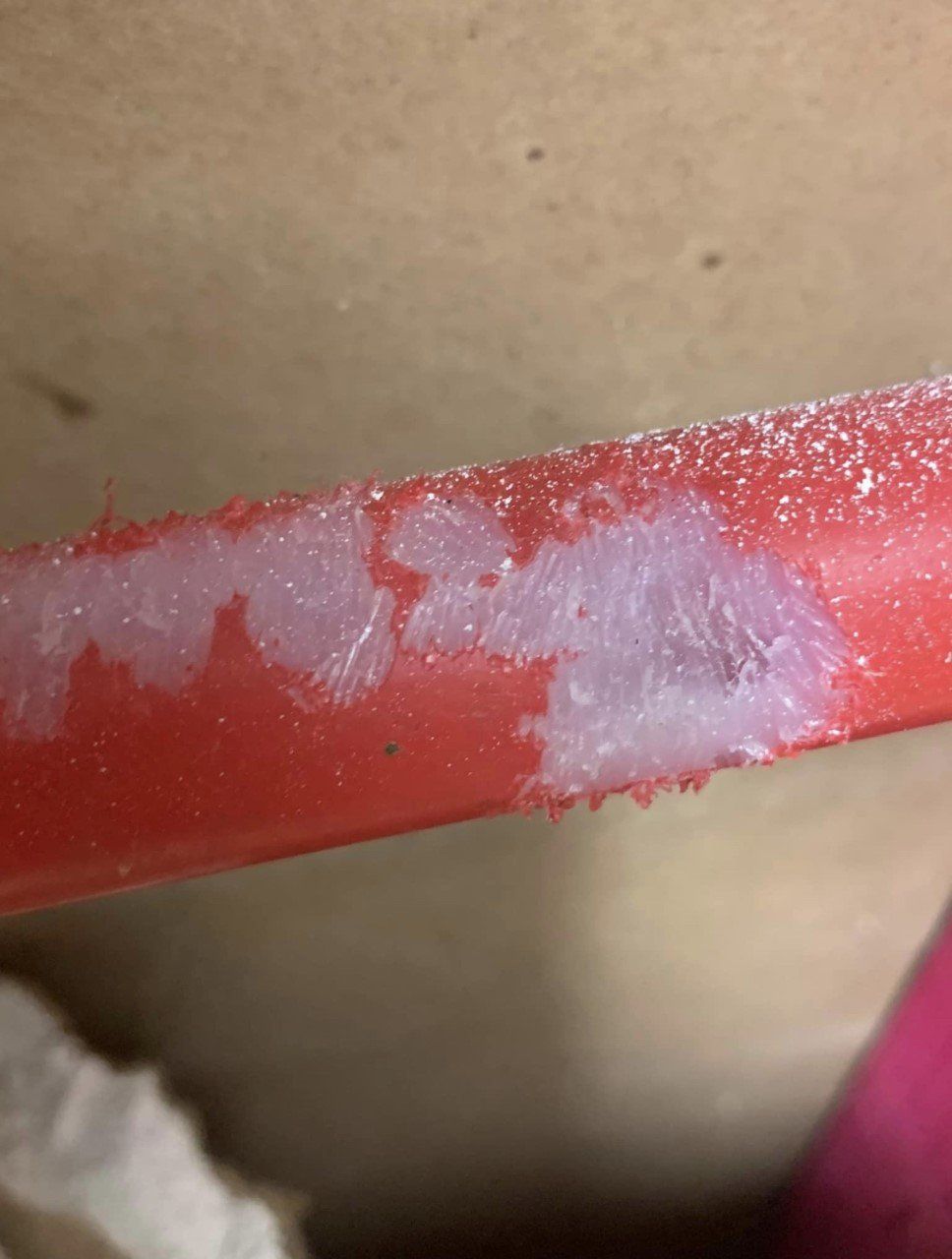 Close-up of a red painted bar with chipped white paint and a rough patch of residue