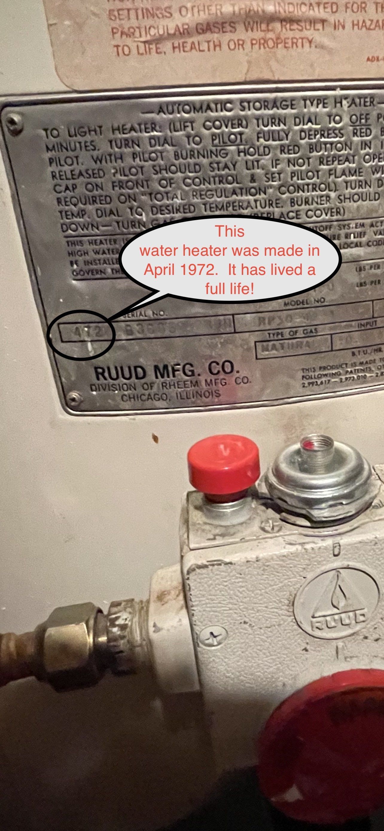 Close-up of a water heater with a metallic nameplate. The nameplate has the manufacturer’s logo, and text with the date April 15, 1972.