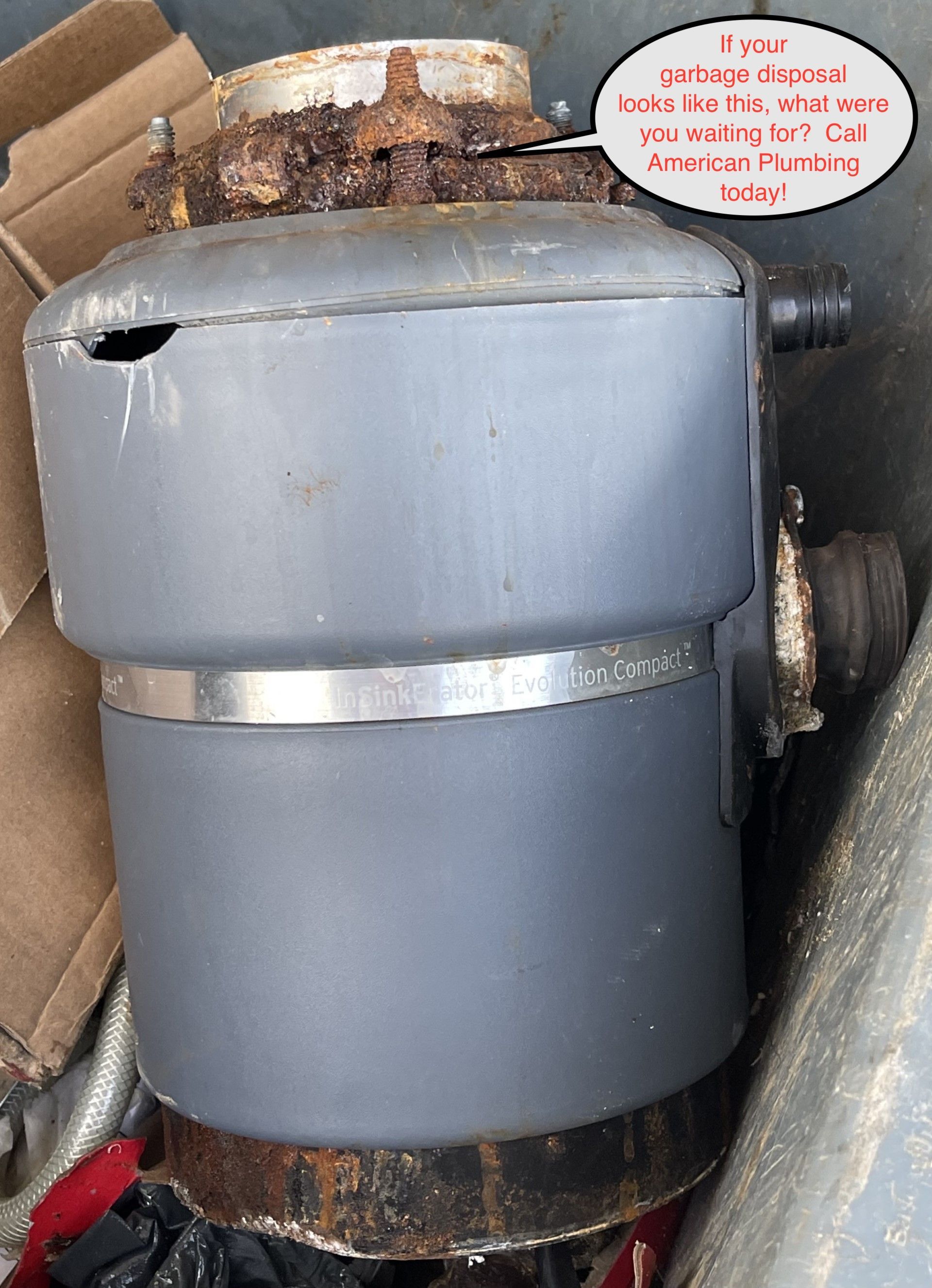 A corroded gray garbage disposal unit, with a rusted top section and metal band around the center.