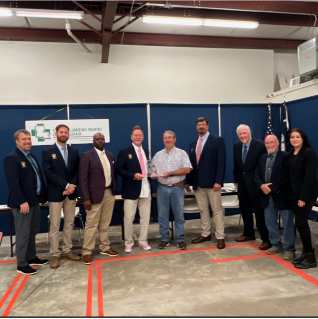 Group of people in suits and casual dress posing in a warehouse-like indoor setting