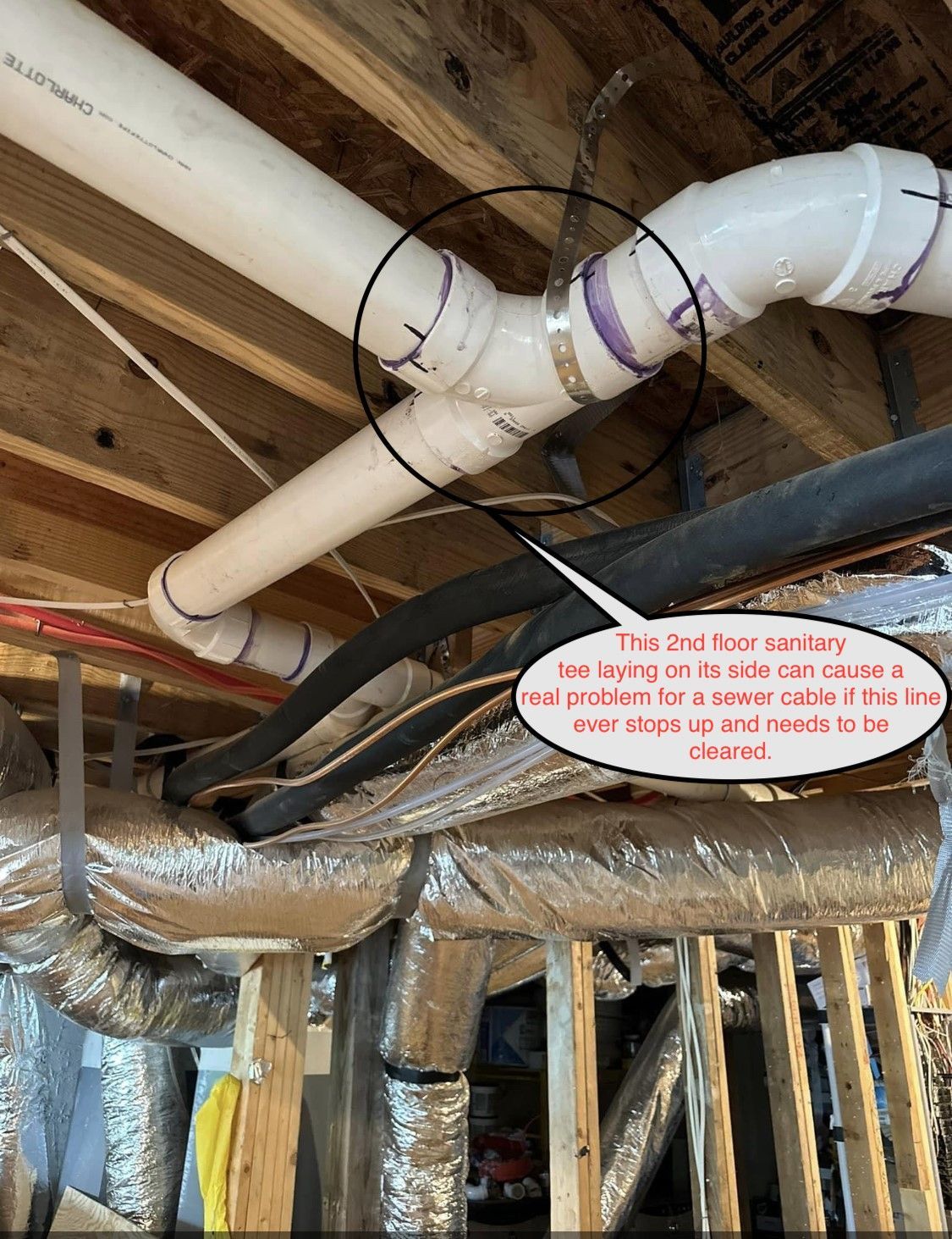 Exposed white PVC ducting and insulated pipes in an unfinished attic with wood rafters and pink insulation.