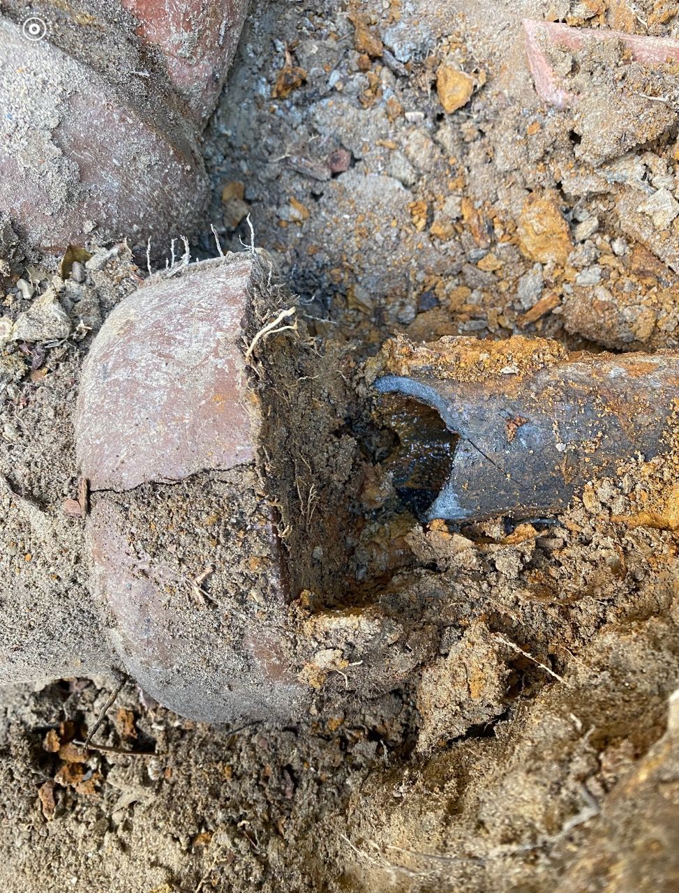 Close-up of a rusted metal bolt embedded in rough dirt and rock